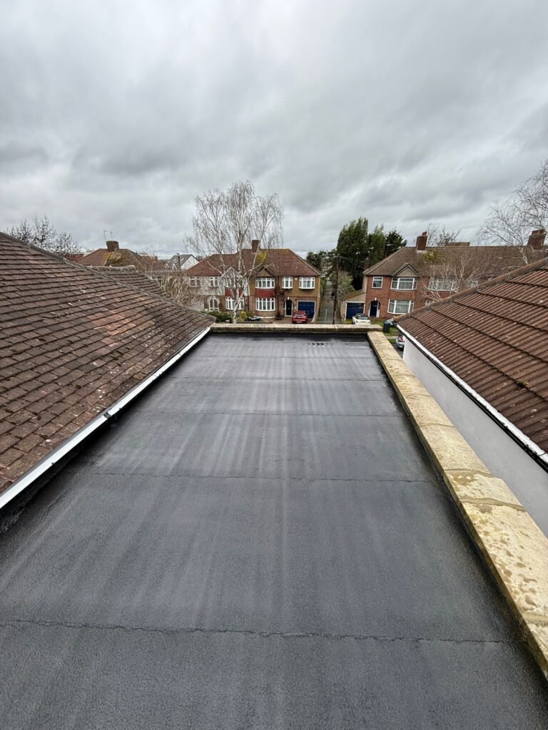 Long flat roof covering between pitched tiled roofs in Hounslow