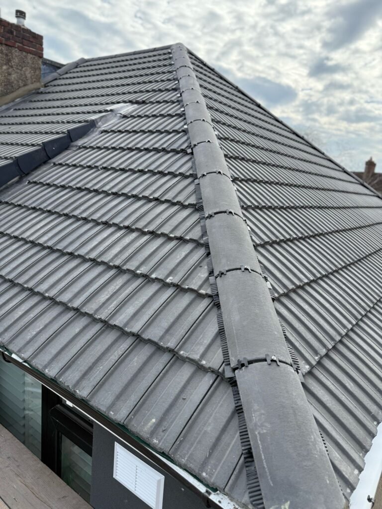 Grey interlocking tiled roof with ridge tiles above a dormer in Hounslow